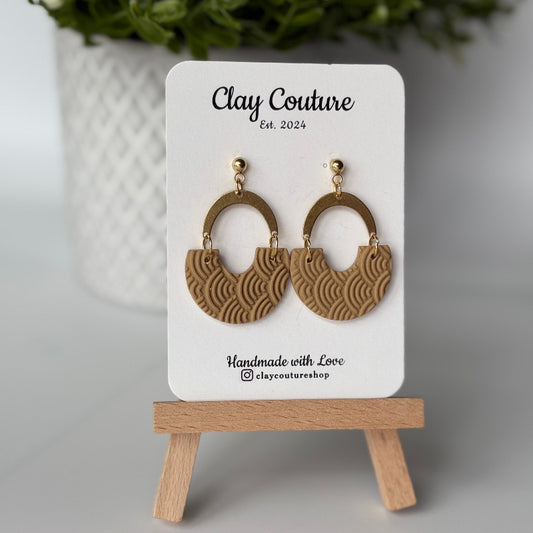 Polymer clay earrings in warm sandstone color with brass connectors and 18K gold plated studs  on a 'Clay Couture' branded card with a wooden stand