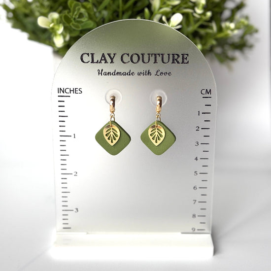 Polymer clay  earrings in Olive Grove color with and gold huggies brass charms on a 'Clay Couture' branded size stand