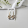 Floral earrings in Ivory color on a Clay Couture branded card with a white background