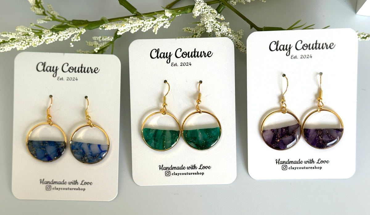 Three pairs of earrings on 'Clay Couture' cards with floral background