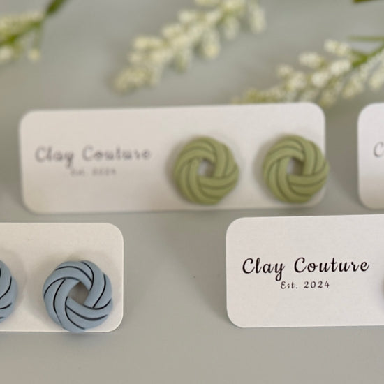 Set ofpolymer clay knot stud earrings on display with labels indicating brand and design.